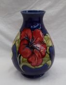 A Moorcroft pottery baluster vase decorated with pink and variegated hibiscus flowers to a blue