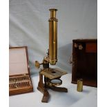 A brass monocular microscope, with rotating mirror, adjustable platform and various lenses,