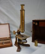 A brass monocular microscope, with rotating mirror, adjustable platform and various lenses,