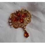 A citrine and pearl brooch of scrolling form set with four oval faceted citrines surrounded by