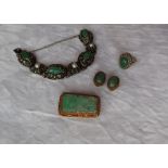A carved jade panel brooch, to a silver gilt floral scrolling setting,