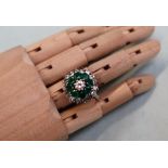 An Emerald and diamond cluster ring, the central round brilliant cut diamond approximately 0.