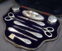 A George V silver manicure set, comprising nail buff, scissors, pots and covers etc, cased,