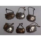 A set of three Elizabeth II silver wine labels, of oval form, decorated with flowers and leaves,