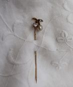 A yellow metal stick pin, set with two round old cut diamonds and a pearl, of leaf form,