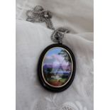 A continental pendant with an oval panel painted with a lake scene with a mountain range beyond,