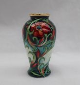 A Moorcroft enamels baluster vase, decorated with flowers and leaves to a green ground,