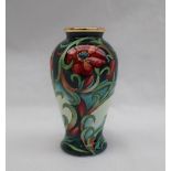A Moorcroft enamels baluster vase, decorated with flowers and leaves to a green ground,