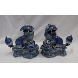 A pair of continental maiolica lion dogs, with foot raised on a ball, with a pierced base,