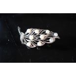 A 14ct white gold brooch in the form of a leaf set with nine pearls each approximately 6mm diameter