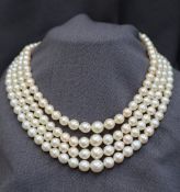 A four strand pearl necklace set with regular shaped pearls to a pearl set yellow metal clasp,