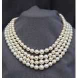 A four strand pearl necklace set with regular shaped pearls to a pearl set yellow metal clasp,