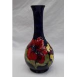 A Moorcroft pottery single stem vase decorated with three pink and variegated hibiscus flowers to a