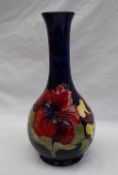 A Moorcroft pottery single stem vase decorated with three pink and variegated hibiscus flowers to a