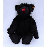 A black mohair Steiff teddy bear with a red nose and articulated body,