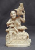 A 19th century Japanese ivory carving of a fisherman, seated upon a basket with birds to his side,