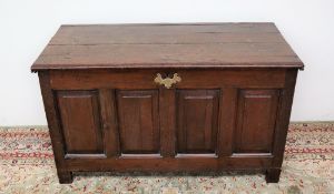 An early 18th century oak coffer, the hinged top above a four fielded panel front on stiles,