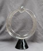 Pino Signoretto - a glass sculpture of circular form holding a sphere on a tapering black glass