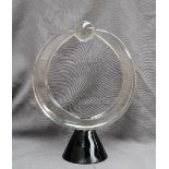 Pino Signoretto - a glass sculpture of circular form holding a sphere on a tapering black glass