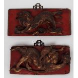 A pair of Chinese carved panels depicting lion dogs, highlighted in red and gilt,