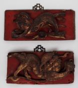 A pair of Chinese carved panels depicting lion dogs, highlighted in red and gilt,