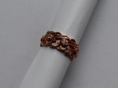 A 14ct yellow gold ring pierced with flowers and leaves set with round brilliant cut diamonds,