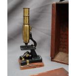 A brass monocular microscope, with a cast iron base,