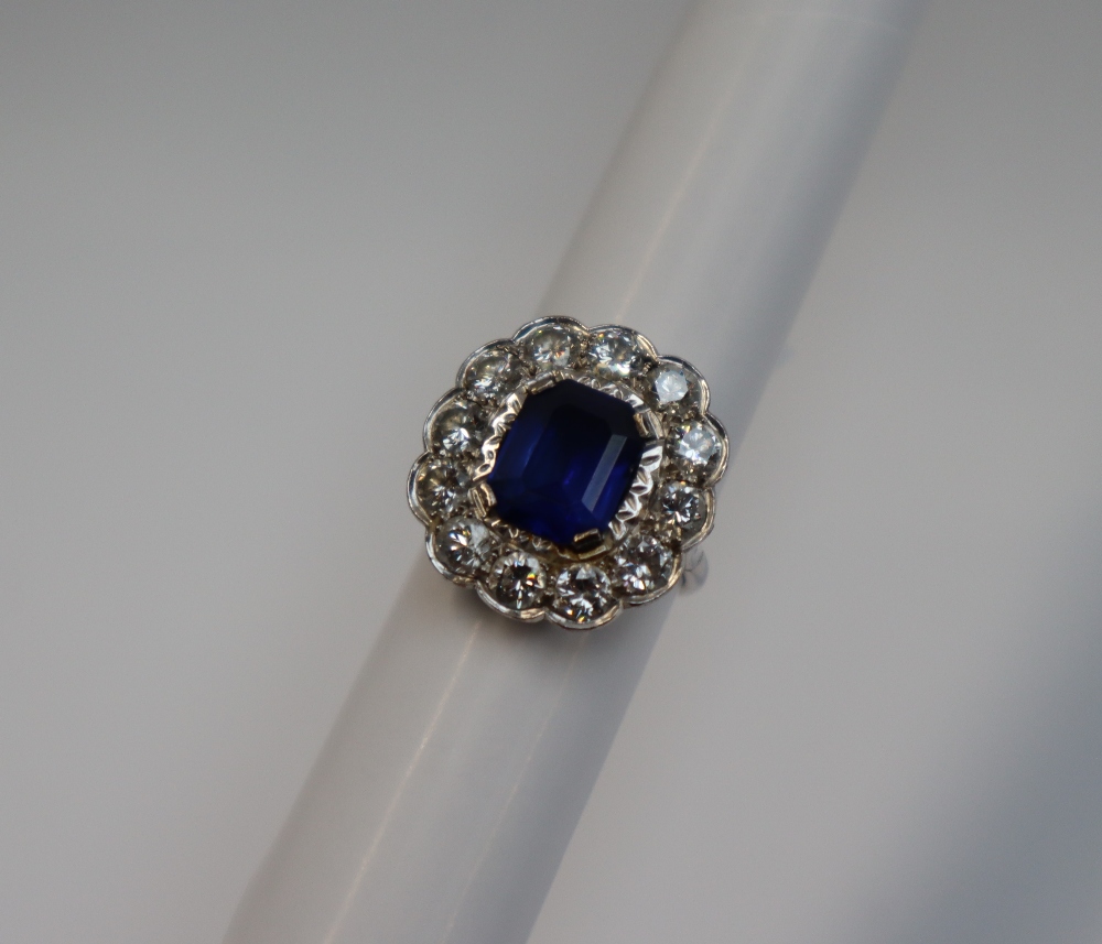 A sapphire and diamond cluster ring, the emerald cut sapphire approximately 11mm x 8mm,