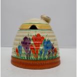A Clarice Cliff beehive shaped preserve pot and cover, painted with crocuses,