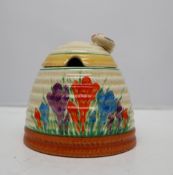 A Clarice Cliff beehive shaped preserve pot and cover, painted with crocuses,