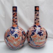 A pair of Japanese Imari bottle vases, with tapering cylindrical necks above a bulbous body,