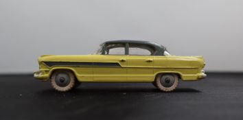 A Dinky Toys diecast model of a Hudson Hornet Sedan, with a yellow body, grey roof and side flashes,