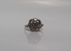 A diamond cluster ring set with eight old cut diamonds to a floral setting, to a white metal shank,