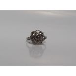 A diamond cluster ring set with eight old cut diamonds to a floral setting, to a white metal shank,