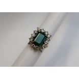 An emerald and diamond cluster ring, the central emerald cut emerald approximately 12mm x 9mm,