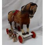 A Steiff pull along horse with well loved mohair body on white rimmed red wheels,