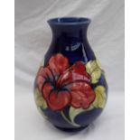 A Moorcroft pottery baluster vase decorated with pink and variegated hibiscus flowers to a blue