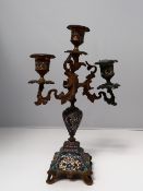 A gilt metal and champleve enamel decorated twin branch candleabra, with scrolling leaf supports,