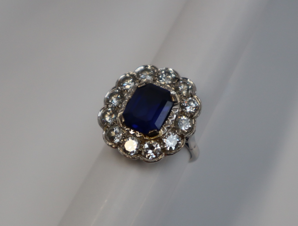 A sapphire and diamond cluster ring, the emerald cut sapphire approximately 11mm x 8mm, - Image 2 of 6