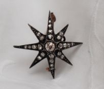 A diamond set brooch of star form, set with old round cut diamonds to a white metal setting,