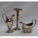 An Edward VII silver cream jug of urn shape with a raised handle on a spreading foot, London,