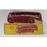 A Dinky Toys diecast model of a Luxury Coach, with a burgundy body, cream coach lines and red hubs,