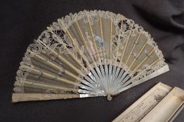 A mother of pearl, bone and lace fan, decorated with a courting couple and floral swags, 24.