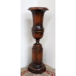 A 20th century mahogany urn, on a cylindrical base and octagonal foot, 73.