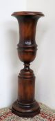 A 20th century mahogany urn, on a cylindrical base and octagonal foot, 73.