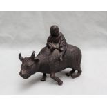 A Chinese white metal figure of a boy riding a water buffalo, patinated to simulate bronze, 10.