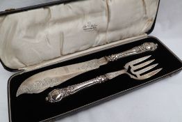 A pair of Victorian silver fish knife and fork servers, engraved with fish and scrolling leaves,