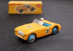 A Dinky Toys diecast model of an Austin-Healey '100' Sports, with a yellow body, blue hubs,