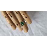 An emerald and diamond ring, the central emerald approximately 7mm x 4mm,