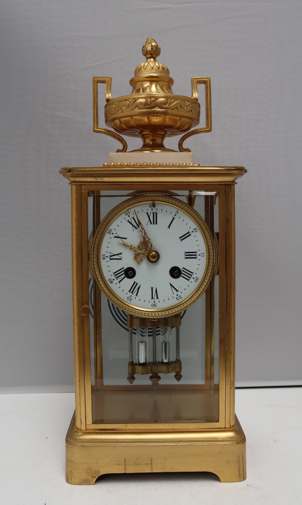 A 19th Century French four glass mantle clock, with a gilt metal vase surmount, on a marble plinth,